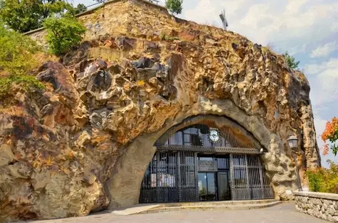 Ingresso monumentale della Chiesa nella Roccia Sziklatemplom a Budapest con cancello in ferro battuto ad arco nella collina Gellért