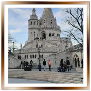 Vista frontale del Bastione dei Pescatori a Budapest con turisti sulla scalinata e cielo parzialmente nuvoloso.