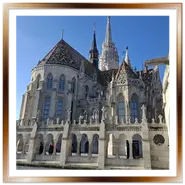Scorcio della Chiesa di Mattia con il suo tetto colorato in maiolica Zsolnay, vista dai loggiati in pietra bianca del Bastione dei Pescatori a Budapest sotto un cielo azzurro.