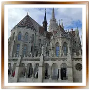 Vista posteriore della Chiesa di Mattia a Budapest con il caratteristico tetto in maiolica colorata e le guglie gotiche, incorniciata dalle arcate bianche del Bastione dei Pescatori.
