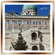 Inquadratura verticale dal basso della monumentale scalinata in pietra e della cupola verde del Palazzo Reale nel complesso del Castello di Buda a Budapest.