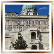 Inquadratura verticale dal basso della monumentale scalinata in pietra e della cupola verde del Palazzo Reale nel complesso del Castello di Buda a Budapest.