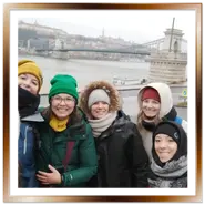 Selfie di un gruppo di turiste sorridenti con giacche invernali davanti al Ponte delle Catene a Budapest.