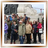 Un gruppo di turisti sorridenti durante una visita guidata ai piedi del monumento Andrássy vicino al Parlamento di Budapest.