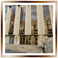 Facciata e scale d'ingresso dell'Hotel Hilton a Budapest con le finestre a specchio che riflettono le guglie e il tetto colorato della Chiesa di Mattia, con una grande roccia in primo piano.