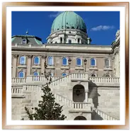 Facciata del Palazzo Reale di Budapest (Castello di Buda) con la grande cupola verde, scalinata monumentale in pietra e cielo azzurro.