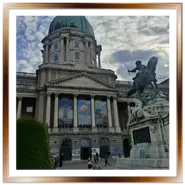 Facciata del Palazzo Reale di Budapest con la cupola verde e l'ingresso della Galleria Nazionale Ungherese, affiancata dal monumento equestre a Eugenio di Savoia, con turisti seduti in primo piano.