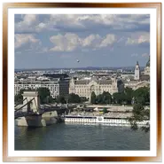 Splendida vista panoramica da Buda verso la sponda di Pest a Budapest. Si notano una sezione del Ponte delle Catene sul Danubio con un grande battello bianco, l'elegante facciata di Palazzo Gresham, le torri della Basilica di Santo Stefano e una mongolfiera nel cielo nuvoloso.