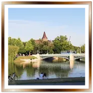 Persone rilassate sulla riva del lago del Parco Cittadino di Budapest con vista sul ponte e sul Castello di Vajdahunyad