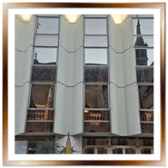 Riflesso della Chiesa di Mattia e del suo tetto colorato sulle finestre a specchio della facciata moderna dell'Hotel Hilton a Budapest.