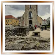 Antiche rovine in pietra delle fondamenta della navata e la svettante gotica Torre di Maria Maddalena a Budapest, sotto un cielo nuvoloso con sole coperto.