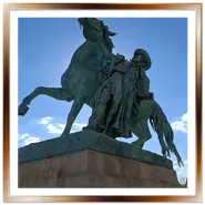Inquadratura dal basso della statua in bronzo con patina verde del mandriano ungherese Csikós che tiene un cavallo impennato, situata vicino al Maneggio Reale nel Castello di Buda.