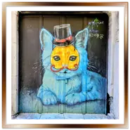 Portone dipinto con la street art di un gatto azzurro con cilindro e maschera nel quartiere ebraico di Budapest