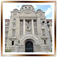 Imponente facciata in stile Art Nouveau dell'edificio storico delle Terme Gellért e dell'Hotel Gellért a Budapest, con il grande portone d'ingresso ad arco e la cupola centrale sotto un cielo parzialmente nuvoloso.