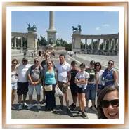 Gruppo di turisti felici in posa con la guida in Piazza degli Eroi a Budapest durante un tour organizzato