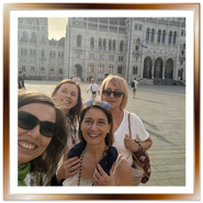 Gruppo di amiche turiste scatta un selfie sorridente nella piazza del Parlamento di Budapest a Pest.