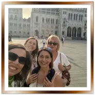 Gruppo di amiche turiste scatta un selfie sorridente nella piazza del Parlamento di Budapest a Pest.