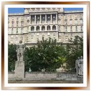 Inquadratura verticale della facciata della Biblioteca Nazionale Széchényi nel complesso del Castello di Buda a Budapest, con il monumento a György Dózsa al centro in primo piano sotto un cielo azzurro.